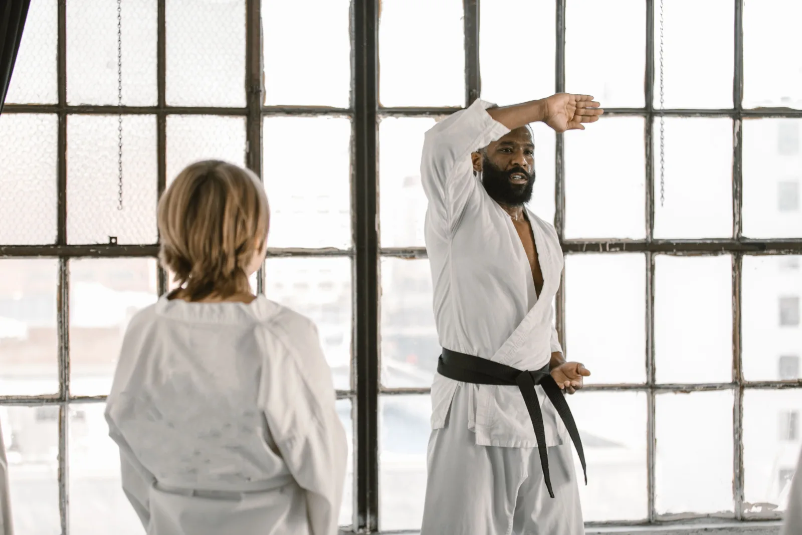 Martial arts instructor demonstrating a technique to a student in a bright studio