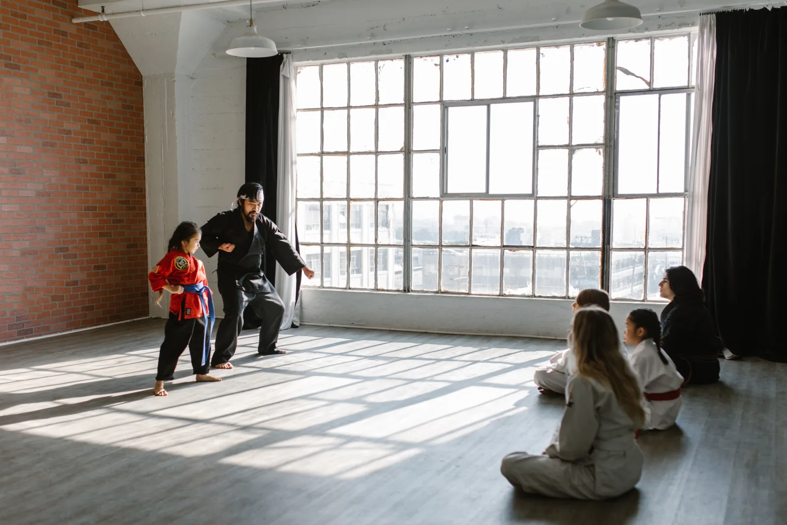 Instructor demonstrating a martial arts technique while a supervised youth class watches